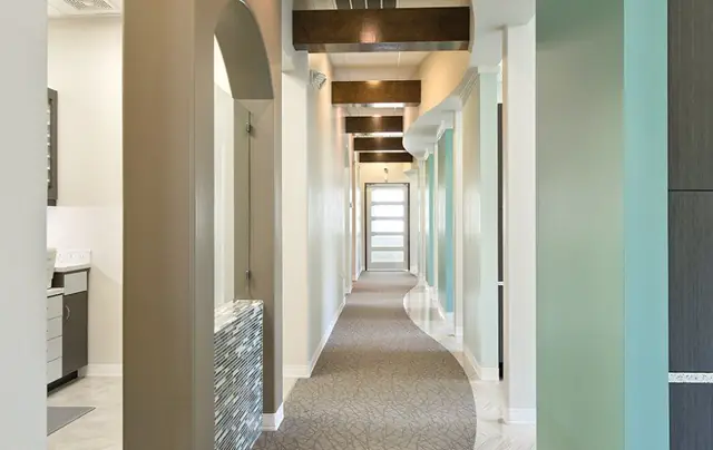 Finished interior corridor with stained beams and a curved carpet inlay, built out by MAG Builders