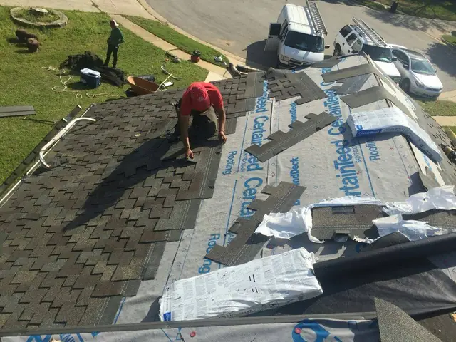 MAG Builders crew laying synthetic underlayment over exposed decking during a tear-off